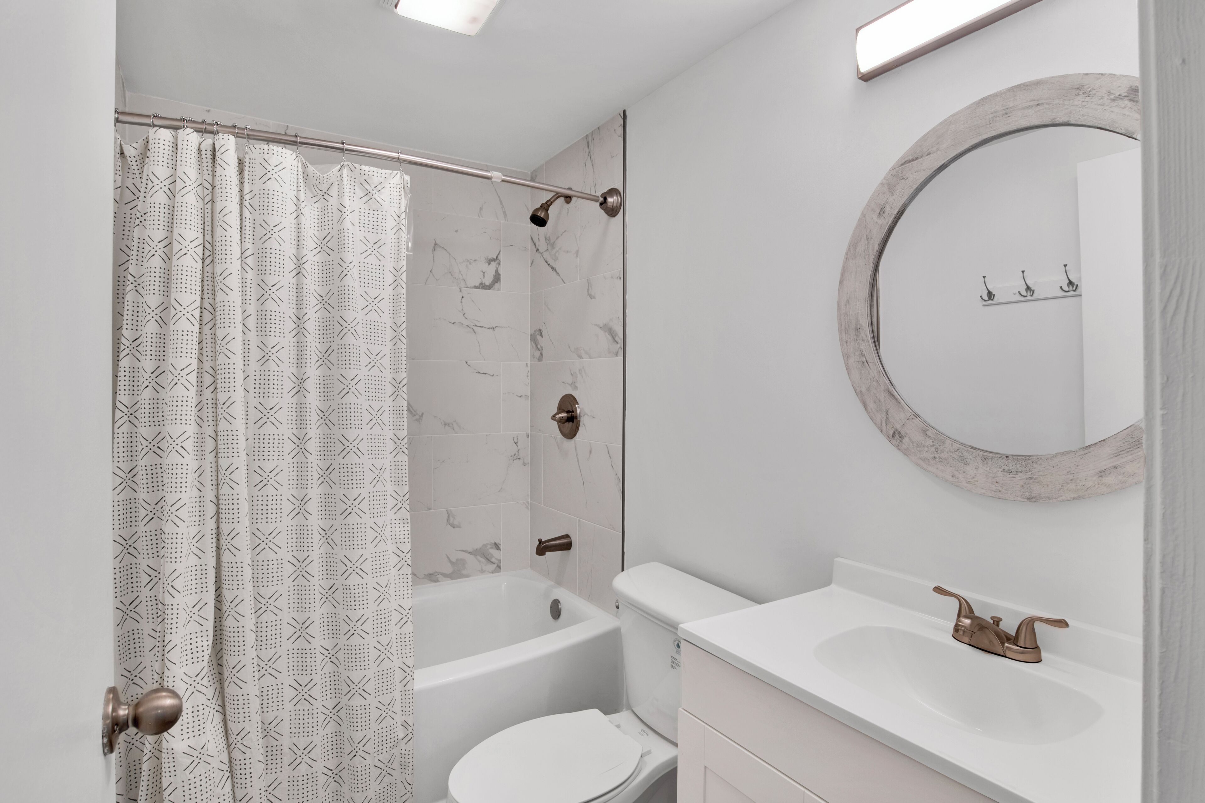 A bathroom with a shower curtain, a bathtub, a toilet, a sink, and a mirror.