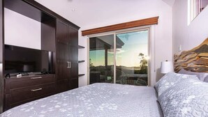 Een slaapkamer met een bed, een televisie, een kledingkast en een schuifdeur die leidt naar een buitenruimte.
