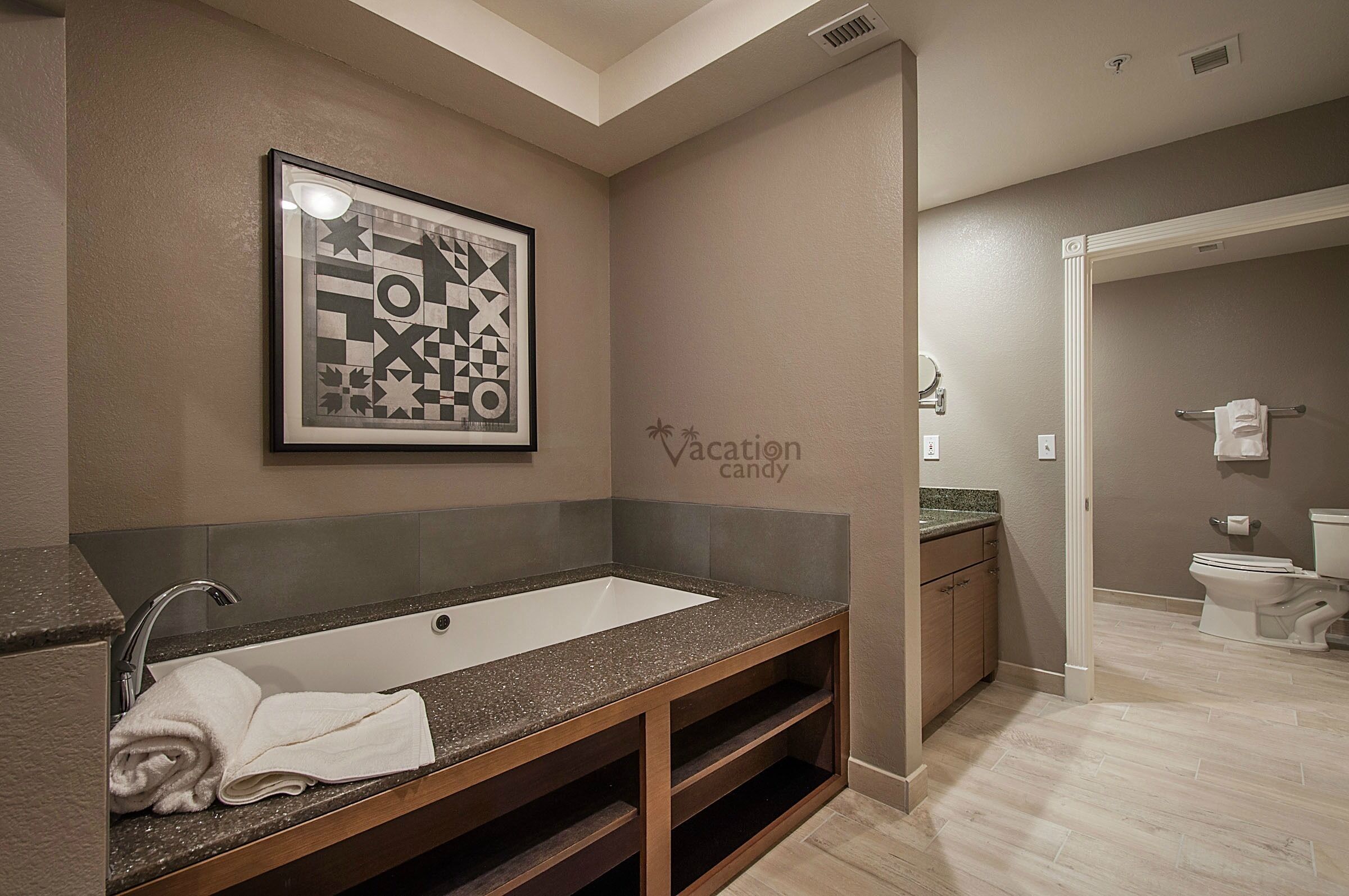 Un baño con un lavamanos grande, tocador de madera y una obra de arte enmarcada en la pared.