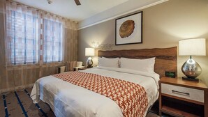 Ein Hotelzimmer mit einem großen Bett, einem Nachttisch mit Lampe, einer Uhr und einem Deckenventilator.