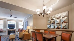 Ein Essbereich mit Holztisch und -stühlen, einer Chandelüster und einem großen Spiegel an der Wand.