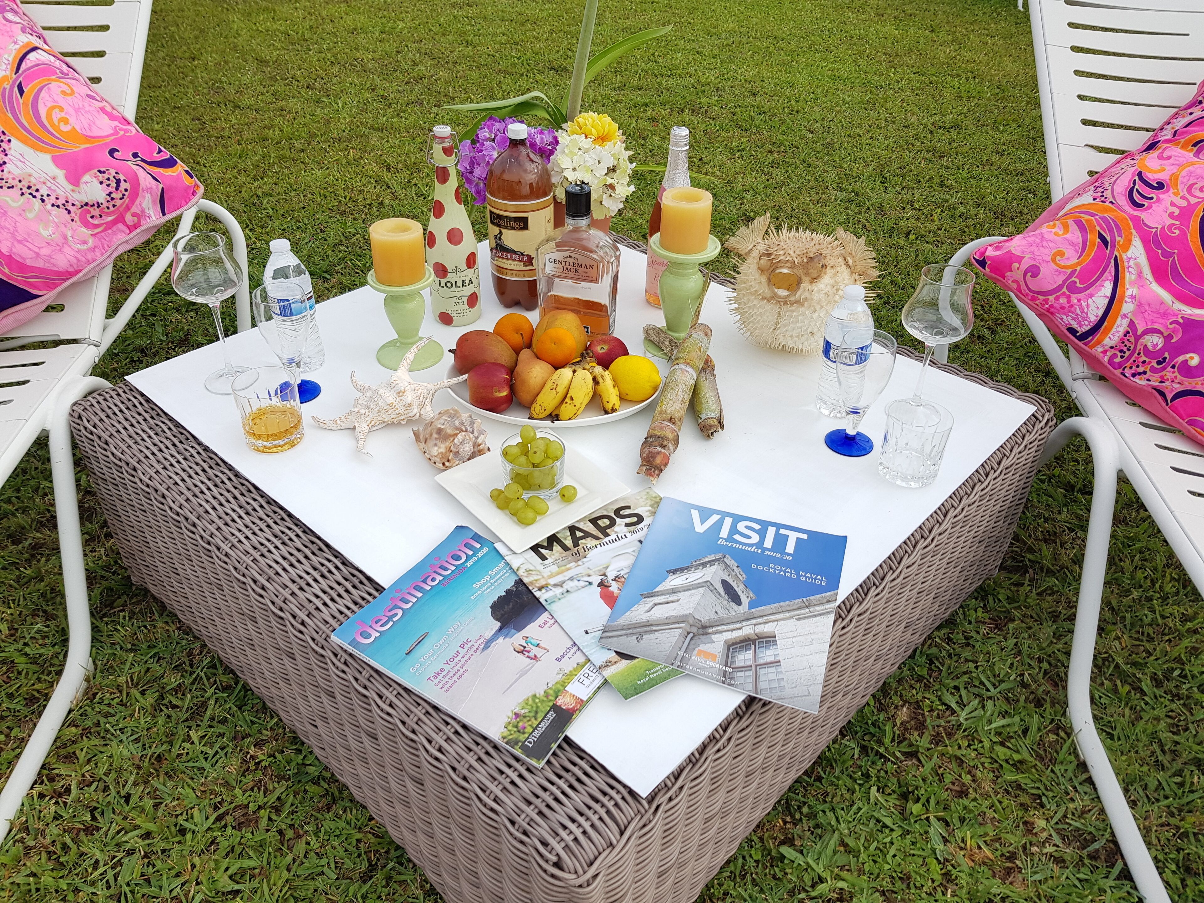 Una mesa al aire libre con diversos alimentos, bebidas y folletos turísticos.