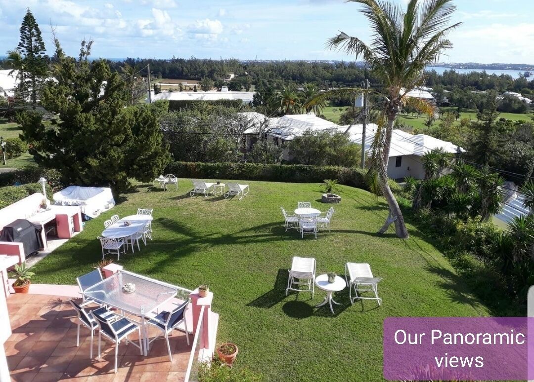 A panoramic view of a property with a well-maintained lawn, outdoor seating area, and a view of the surrounding landscape.