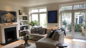 A living room with a fireplace, a sofa set, a coffee table, and a large window with a view of the outside.