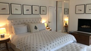 A bedroom with a large bed, a dresser, a TV, and framed pictures on the wall.