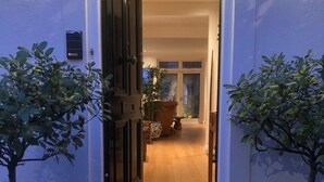 A doorway leading into a house with a wooden floor and a potted plant on the right.