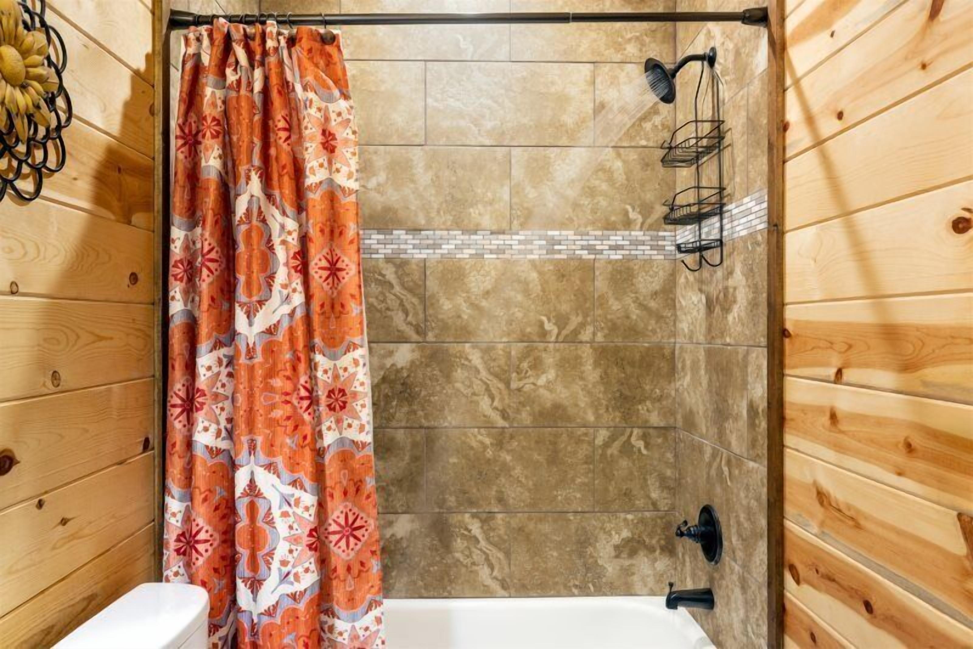 Ein Badezimmer einer Holzhütte mit Dusche, Toilette und gefliesten Wänden.