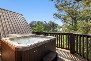A hot tub on a wooden deck with a railing, surrounded by trees. - Majestic Mountain Lodge in Hochatown/Broken Bow, OK (Broken Bow)