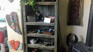 Een rustieke kamer met een houten boekenkast, een aan de muur bevestigde plant, een decoratief hart en een houtkachel.