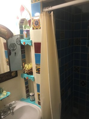 Un baño con lavamanos, espejo y cortina de ducha.
