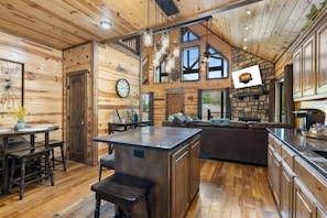 A spacious kitchen with wooden cabinetry, a central island, and a dining area with a round table and chairs.