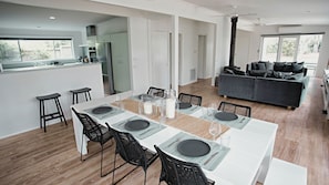 A modern kitchen with a dining area, a sofa, and a large window.
