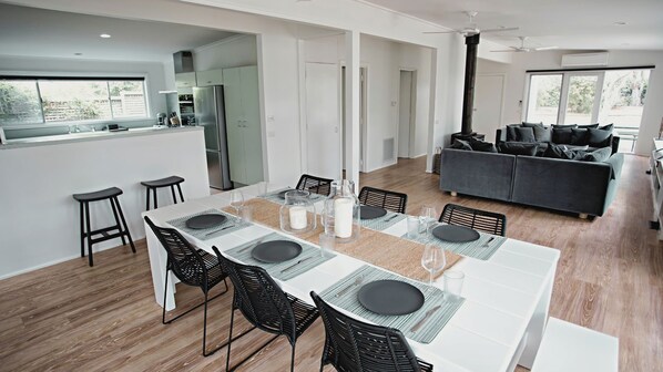 A modern kitchen with a dining area, a sofa, and a large window.
