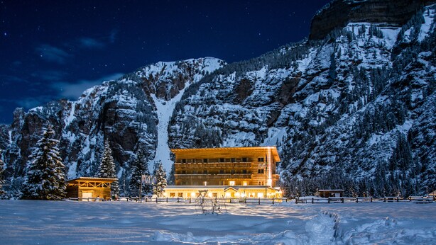 A snow-covered mountain with a wooden building in the foreground. - Pederü (Marebbe)