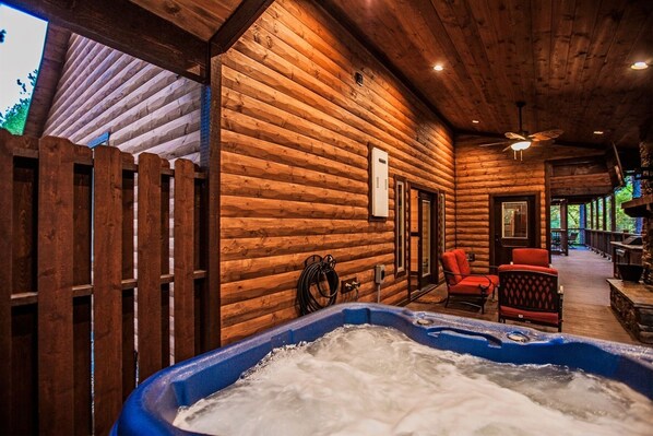 A wooden cabin interior with a hot tub, wooden walls, and a ceiling fan.
