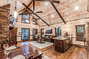 A spacious log cabin interior with a dining area, living room, and kitchen.