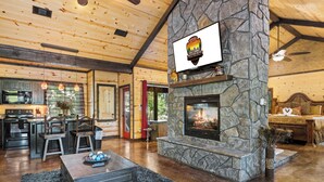 Ein gemütliches Lodge-Interieur mit Kamin aus Stein, Holzbalkendecke und einem Essbereich.