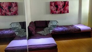Een kamer met twee bedden, een slaapbank en een spiegel.