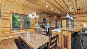 Ein Holzblockhaus-Interieur mit Küche, Essbereich und großen Fenstern.