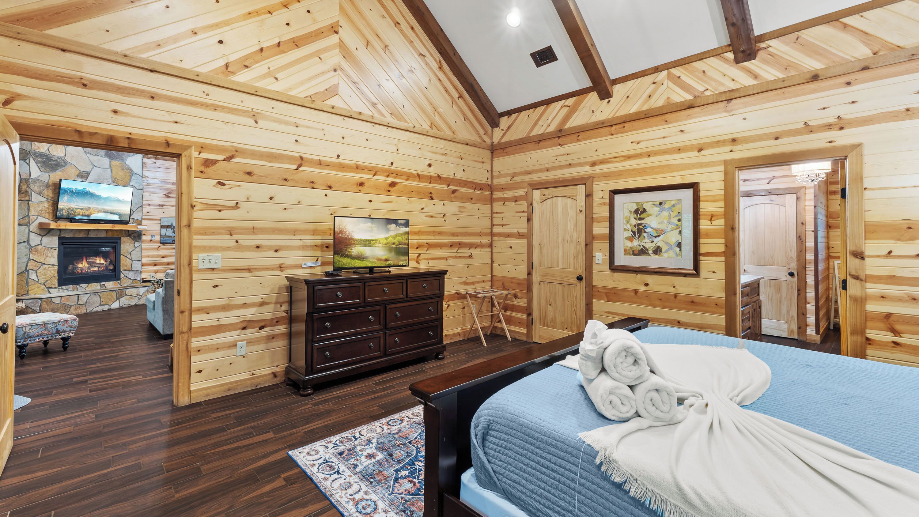 L’intérieur d’un chalet en bois, avec un lit, une commode, une cheminée et un téléviseur.