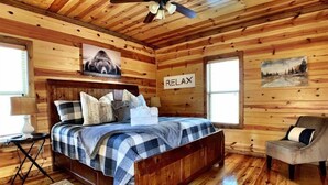 Une chambre confortable, aménagée dans un chalet en bois, avec un lit, une chaise et un panneau indiquant « RELAX » accroché au mur.