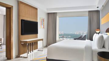 Una habitación de hotel moderna con una cama grande, un televisor de pantalla plana en la pared, un escritorio y vistas a la ciudad a través de un ventanal amplio.