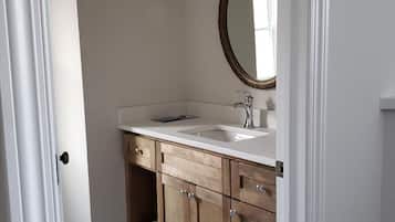 A bathroom with a white sink, wooden cabinets, a mirror, and a blue bath mat.