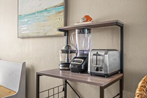 A kitchen counter with a blender, toaster, and a decorative item on a shelf. - Cute Family Friendly Beach Condo! (St Pete Beach)