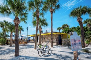 Un edificio sul lungomare con facciata in pietra, una bicicletta parcheggiata davanti e un cartello che indica l'accesso alla spiaggia.