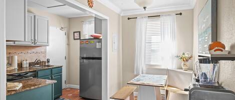 A kitchen with a refrigerator, a sink, and a window with curtains.