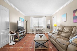 A living room with a television, a sofa, a coffee table, and a dining area with a table and chairs.