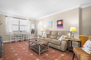 A living room with a sofa, coffee table, and a dining area with chairs and a table.