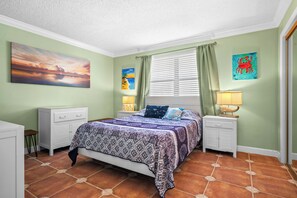 Una camera da letto con un letto, comodini, una finestra con tende e opere d'arte alle pareti.