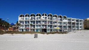 A beachfront hotel with multiple balconies, a sandy beach in front, and a clear blue sky. - Ambassador 126 - Gulf Front (Panama City Beach)