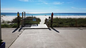 A beach entrance with a wooden gate, a concrete pathway, and a view of the ocean. - Ambassador 126 - Gulf Front (Panama City Beach)