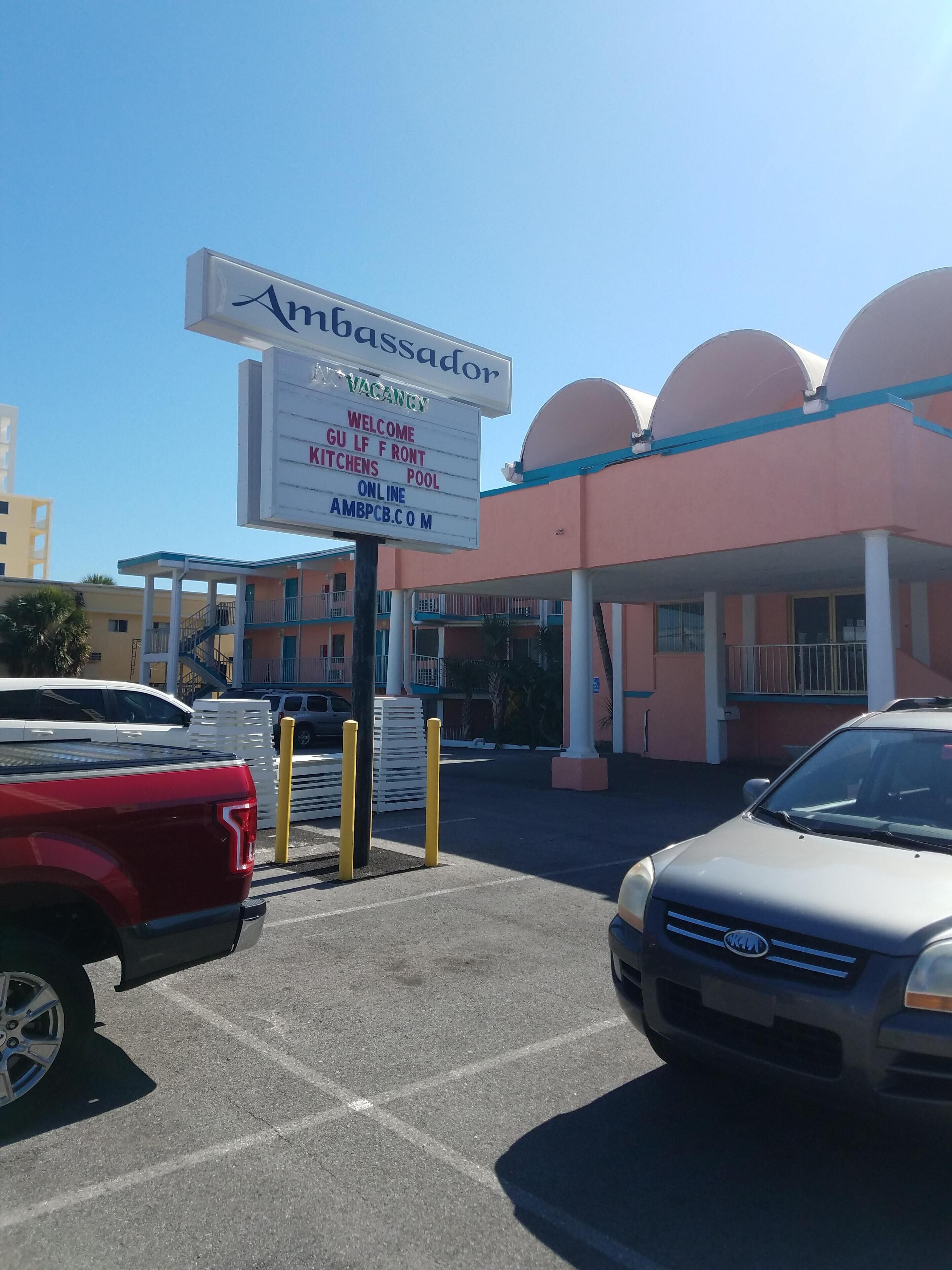 Une enseigne pour l’hôtel Ambassador, indiquant qu’il propose des équipements tels qu’une cuisine, un salon et une piscine.