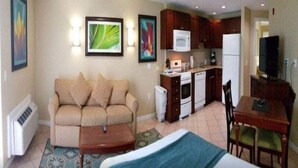 Quarto de hotel compacto com cozinha compacta, sofá, cama e área de refeições.
