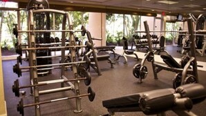 Uma academia com diversos equipamentos de ginástica, incluindo aparelhos de musculação e pesos livres.