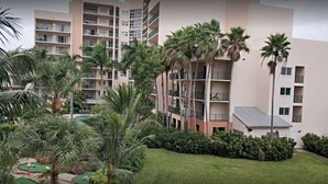 Hotel com vários andares e um pátio central com palmeiras e uma pequena área de piscina.