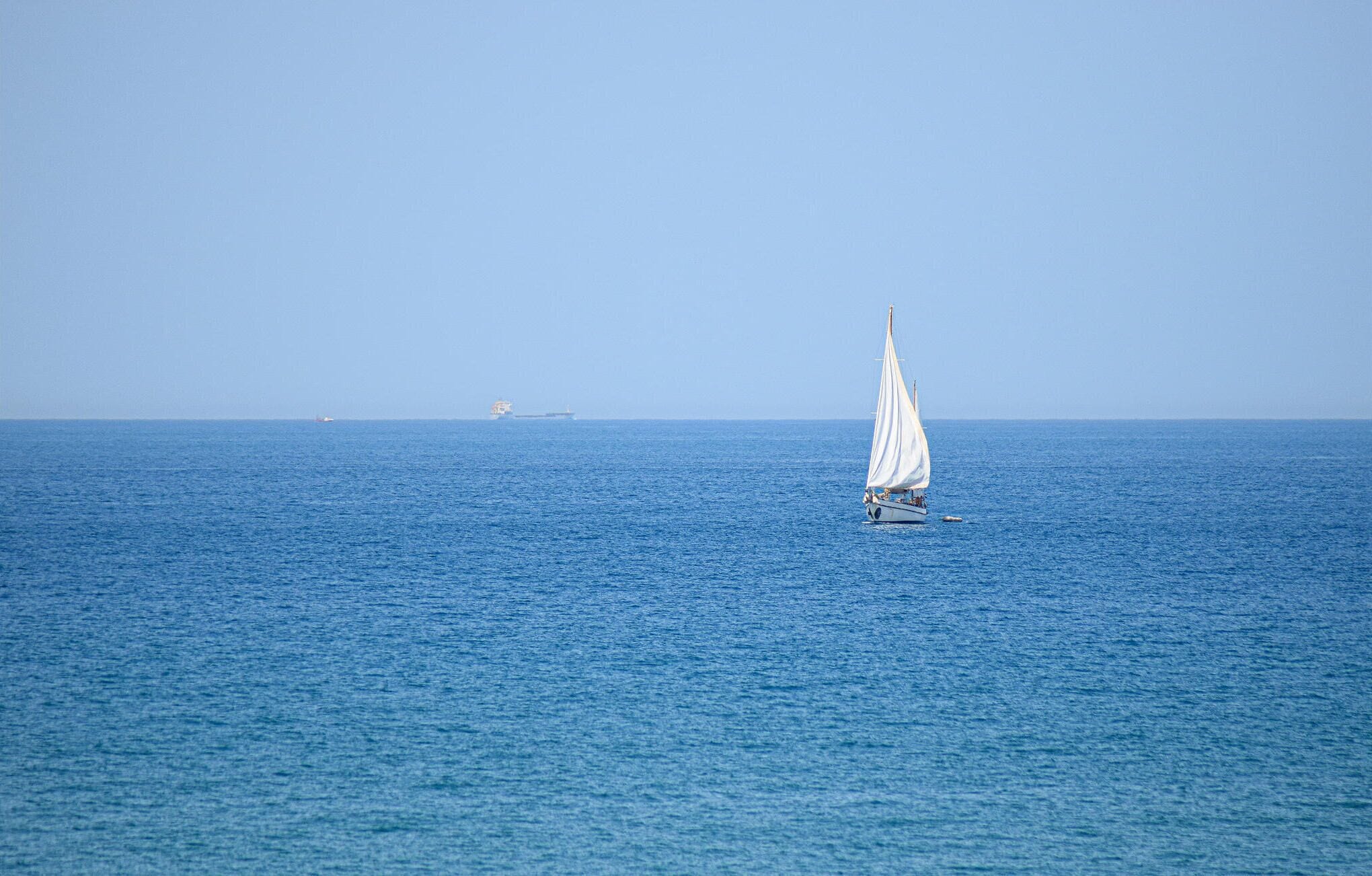 Ein Segelboot auf ruhiger See unter blauem Himmel.