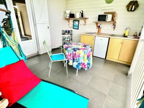 A compact kitchen with a refrigerator, microwave, and a small dining area with a table and chairs.