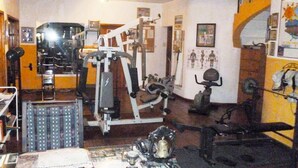 Une salle de sport équipée de divers appareils d’exercice, notamment un tapis de course, des vélos d’appartement et des appareils de musculation.