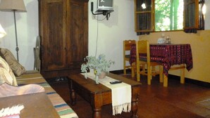 Un salon traditionnel avec un meuble en bois, un téléviseur, une table à manger avec des chaises et une fenêtre avec des rideaux.