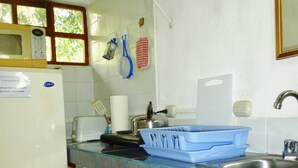 Une cuisine équipée d’un réfrigérateur, d’un four à micro-ondes, d’un évier et de meubles de rangement en bois.