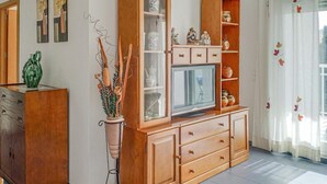 Ein Wohnzimmer mit einem Holzschrank, einem Fernseher und Dekorationselementen.