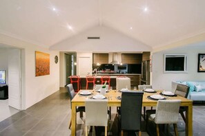A dining area with a table set for four, a kitchen in the background, and a living area with a sofa.