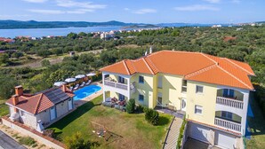 A two-story building with a swimming pool, surrounded by greenery and a view of the sea. - Awesome home in Turanj (Turanj)