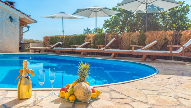 A swimming pool with lounge chairs and umbrellas, a bottle of champagne, and a plate of fruit. - Awesome home in Turanj (Turanj)