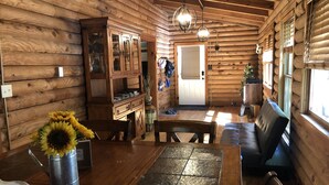 L’intérieur chaleureux d’un chalet avec des murs en bois, un coin repas comprenant une table et des chaises, un meuble encastré et un banc.