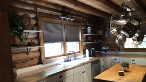 Une cuisine avec des murs en bois, un évier, des placards et une table à manger.